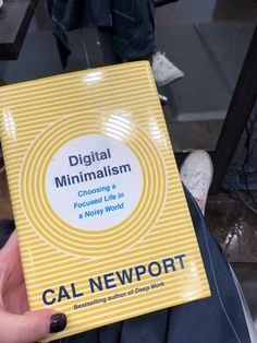 a person holding up a yellow book with the title digital minimalism choosing me in a new world