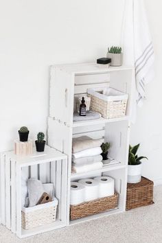 a white shelf filled with lots of towels and other items next to a potted plant