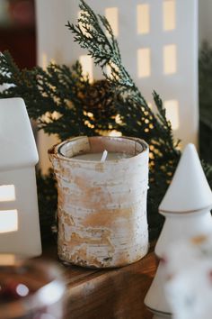 a candle that is sitting on a table next to some christmas tree branches and other decorations