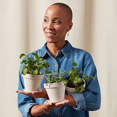 a woman holding two potted plants in her hands