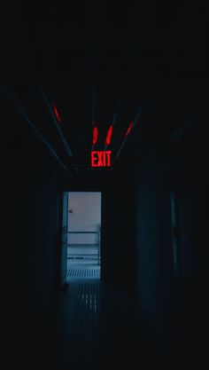 an exit sign is lit up in the dark with red light coming from behind it