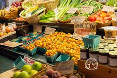 an assortment of fruits and vegetables on display at a market stall with labels for sale