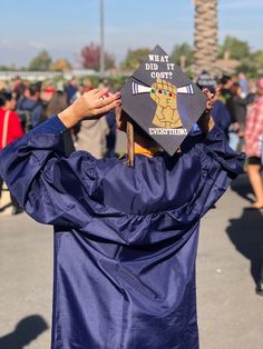 a person wearing a graduation cap and gown holds their hat up to the camera with both hands