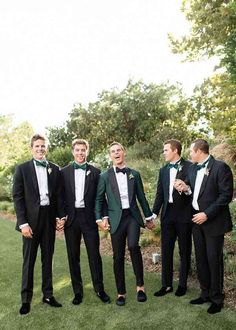 a group of men standing next to each other on top of a lush green field