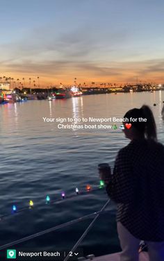 two people standing on the deck of a boat looking out at the water and lights