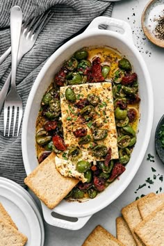 a white bowl filled with fish and vegetables next to crackers