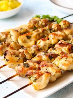 chicken skewers are sitting on a white plate