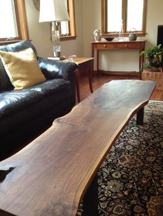 a wooden table sitting in the middle of a living room next to a black couch