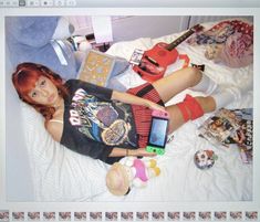 a doll laying on top of a bed next to a cell phone and other items