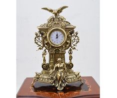 an antique clock is sitting on top of a wooden box with gold decorations and birds