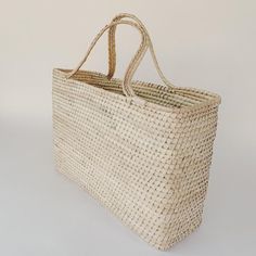 a large woven bag on a white surface with no handles or handles, sitting in front of a wall