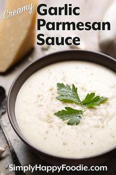 creamy garlic parmesan sauce in a black bowl with fresh herbs on the side