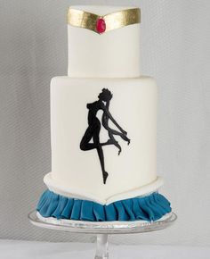 a white cake with blue ruffles and a silhouette of a kissing couple on top