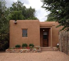 a small adobe house with steps leading to the front door