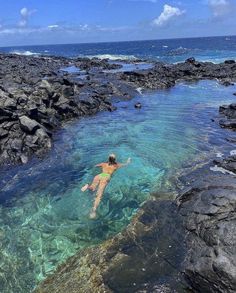 a woman swimming in the ocean next to rocks