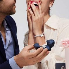 a man and woman holding something in their hands while they look at each other's rings