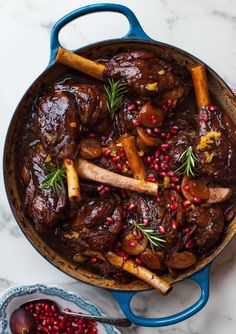 a pot filled with meat and vegetables on top of a white marble counter next to a blue skillet