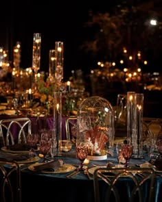 the table is set with candles, plates and vases for an elegant dinner party