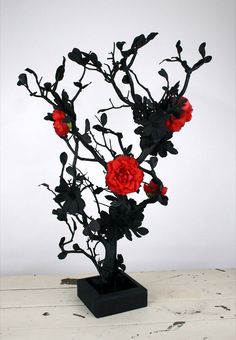 a black vase with red flowers in it