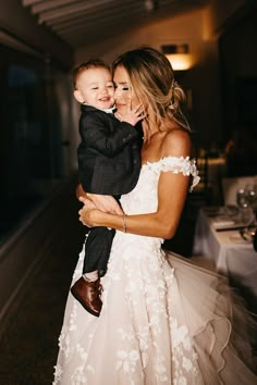 a woman in a wedding dress holding a small child wearing a tulle skirt with white flowers on it