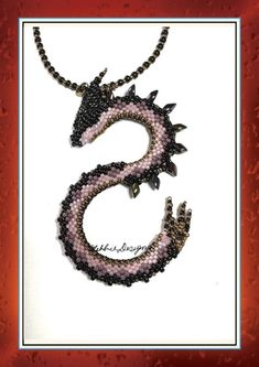 Crafted with meticulous attention to detail, this handmade 3D beaded S shaped black, purple and bronze dragon necklace is a mesmerising piece of wearable art. The intricate design features a captivating dragon motif that adds a touch of mystique to any outfit.  This dragon necklace is a must have for any jewellery collector, so add a touch of fantasy and sophistication to your ensemble.  This necklace was made with Magatamas, Miyuki, Delica and Toho Japanese Glass Seed Beads, in the colours blac Handmade Black Fantasy Necklaces, Beaded Dragon, Dragon Motif, Bronze Dragon, Dragon Necklace, Dragon Pendant, Intricate Design, Wearable Art, Seed Beads