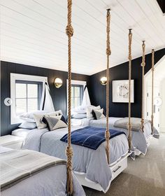 two beds in a room with rope hanging from the ceiling and one bed on the other side