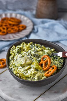 a bowl filled with guacamole and some pretzels on the side