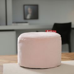 a pink ottoman sitting on top of a wooden table