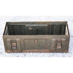 an old metal box with two handles on the top and bottom, sitting on concrete