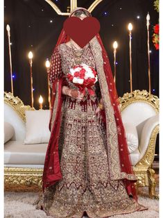 a woman in a red and gold bridal gown standing next to a white couch