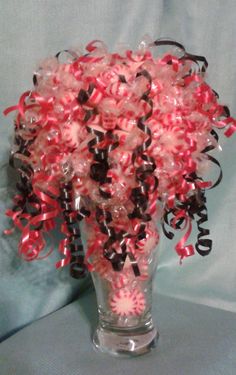 a vase filled with red, black and white streamers on top of a bed