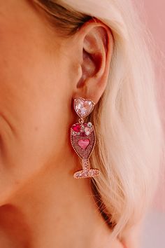 - Keep love in your heart and champagne in you glass this Valentine's Day with these shimmering earrings! - Rose gold colored metal material - Rhinestone heart studs with dangling glittery champagne glass design featuring rhinestone heart accents - Length: 2.5 Glamorous Pink Jewelry For Celebration, Glamorous Pink Earrings For Celebration, Crystal Heart Drop Earrings For Party, Glamorous Rhinestone Heart Earrings For Party, Glamorous Rose Gold Jewelry For Celebration, Rhinestone Jewelry For Valentine's Day Party, Glamorous Heart Drop Earrings For Valentine's Day, Glamorous Heart Earrings For Valentine's Day, Pink Jewelry For Valentine's Evening