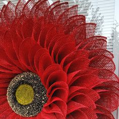 a large red flower with yellow center sitting in front of a white door and window