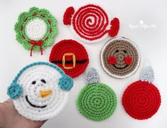 crocheted christmas ornaments are displayed on a white surface with a person's hand