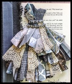 an altered book page with many pieces of fabric