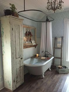 an old fashioned bathtub in a bathroom with wood floors and white paint on the walls