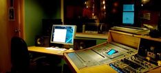 a recording studio with sound mixing equipment and other electronic equipment on the desk in front of it