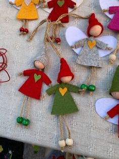 several small christmas elves are hanging from twine strings on a table with other decorations