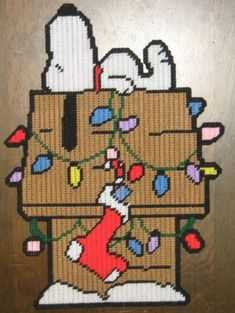 a cross stitch christmas stocking bag with snoopy on it's bottom and lights all around