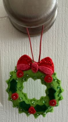 a green christmas wreath hanging on the front door with a red bow and sequins