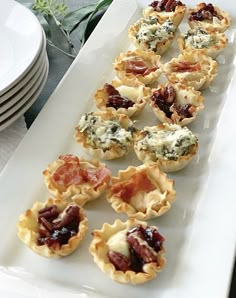 small appetizers are lined up on a white platter