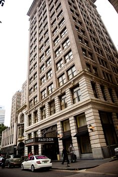 a tall building sitting on the side of a street next to traffic and people walking