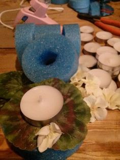 some candles are sitting on a table with flowers and other items around it, including a blue vase