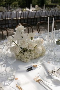 the table is set with white flowers and silverware