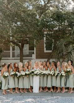 a group of women standing next to each other in front of a tree and building