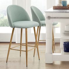 two light blue bar stools in front of a white kitchen island with plates on it