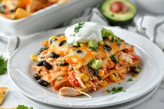 an enchilada with black beans, avocado and sour cream on top