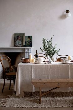 the table is set for two with plates and glasses on it, near a fireplace