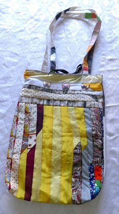 a multicolored purse sitting on top of a white tablecloth covered bed sheet