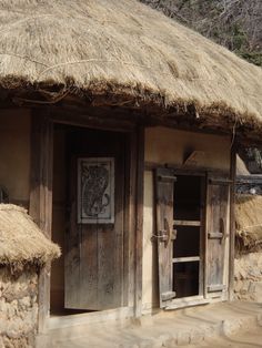 an old hut with thatched roof and wooden doors